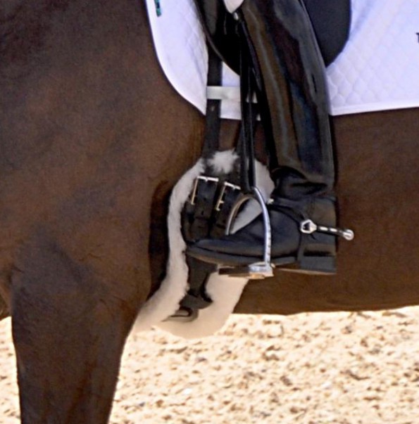 Dieser Kurzgurt hat gerade noch die richtige Länge, um das Pferd nicht am Ellbogen zu behindern. Idealerweise wäre er etwas länger, was aber vermutlich den Sitz der Reiterin behindern würde. (© Equestrian, Wikipedia)
